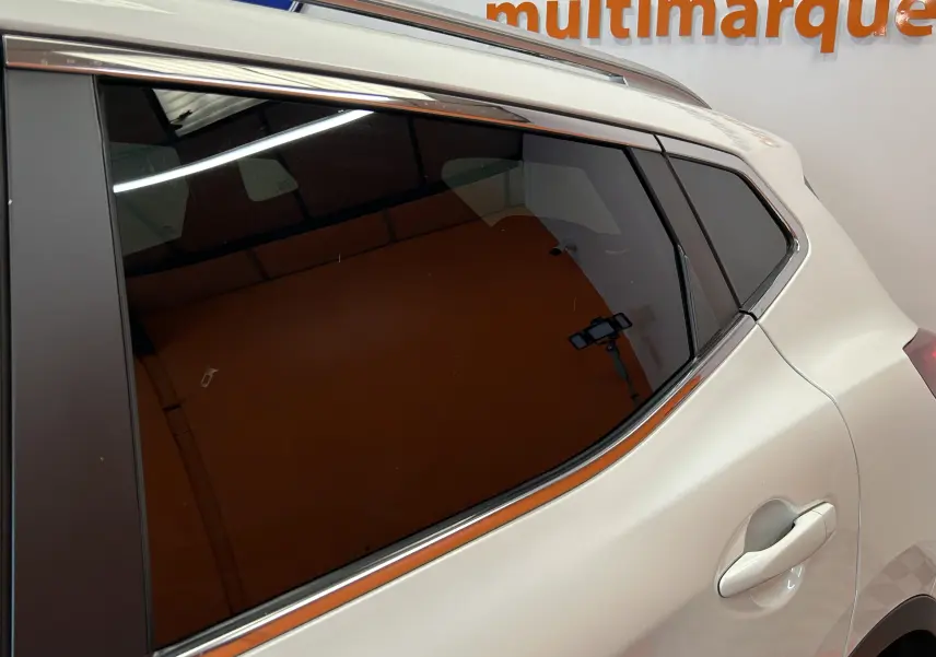 Vue rapprochée du côté arrière droit d’un Nissan Qashqai blanc avec vitrage teinté et poignée de porte visible.