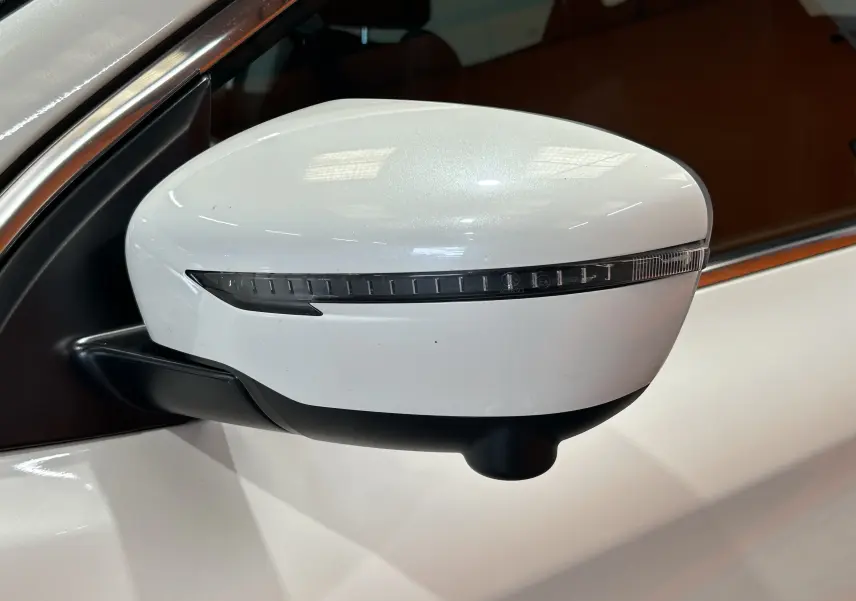 Rétroviseur droit blanc du Nissan Qashqai 2018 avec clignotant intégré, vue rapprochée sur fond intérieur sombre.