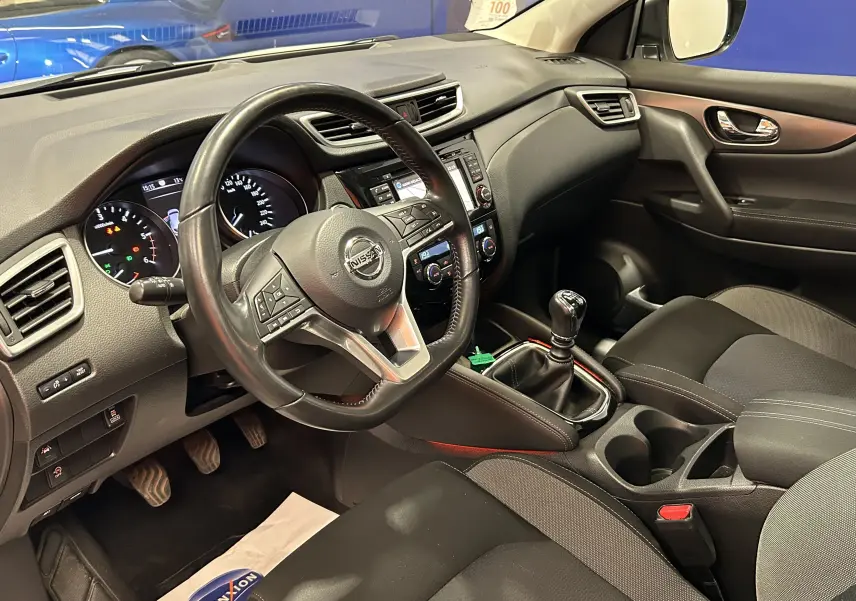 Vue intérieure côté conducteur du Nissan Qashqai 2018, tableau de bord noir avec volant cuir et boîte manuelle.