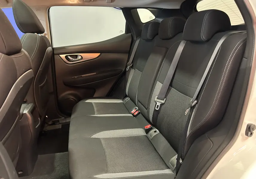 Vue intérieure côté droit des sièges arrière noirs en tissu du Nissan Qashqai blanc, avec ceinture de sécurité et porte ouverte.