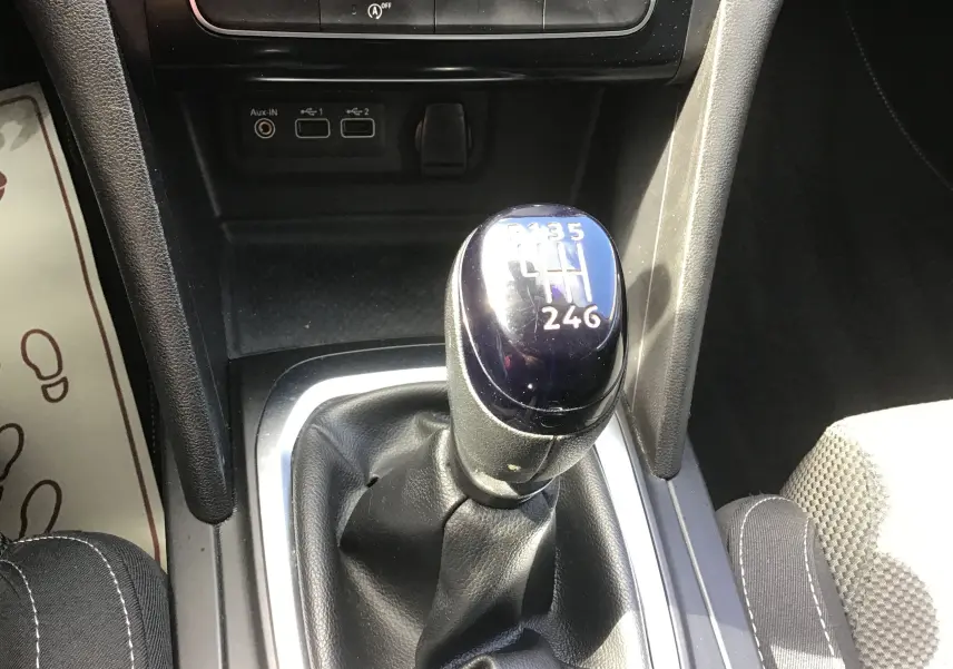 Gros plan sur le levier de vitesses manuel noir de la Renault Mégane IV Société blanche, avec console centrale et ports USB visibles.