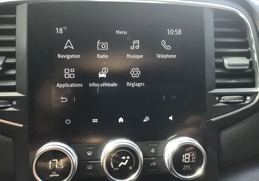 Vue rapprochée de l'écran tactile central et des commandes de climatisation du Renault Mégane IV Société blanc, version 2021.