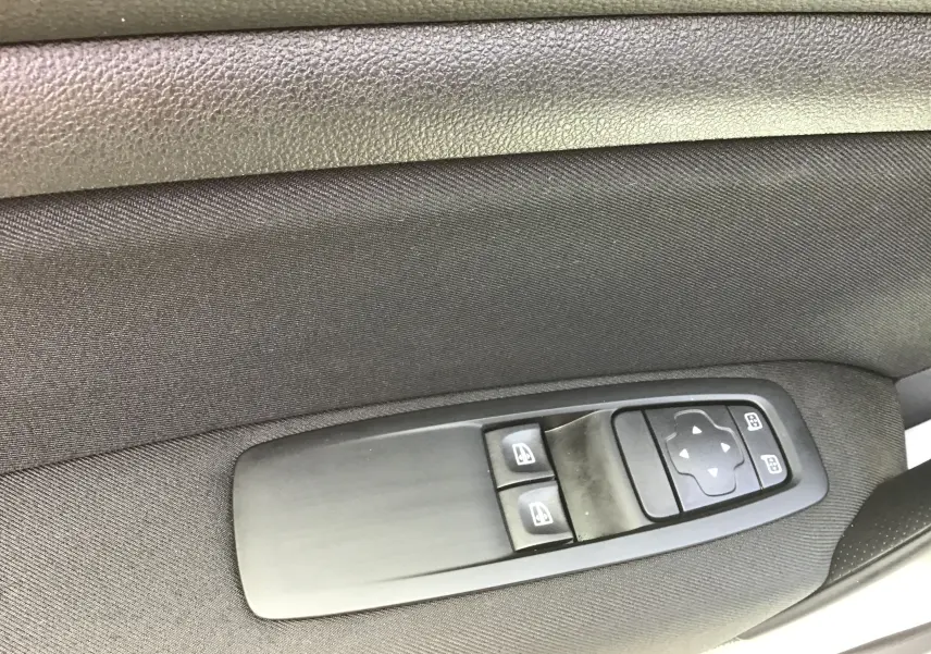 Commande des vitres électriques et réglage des rétroviseurs sur la porte intérieure côté conducteur d'une Renault Mégane IV Société blanche.