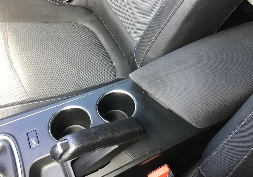 Gros plan sur la console centrale noire et les sièges tissu gris foncé de la Renault Mégane IV Société blanche, version 2021.