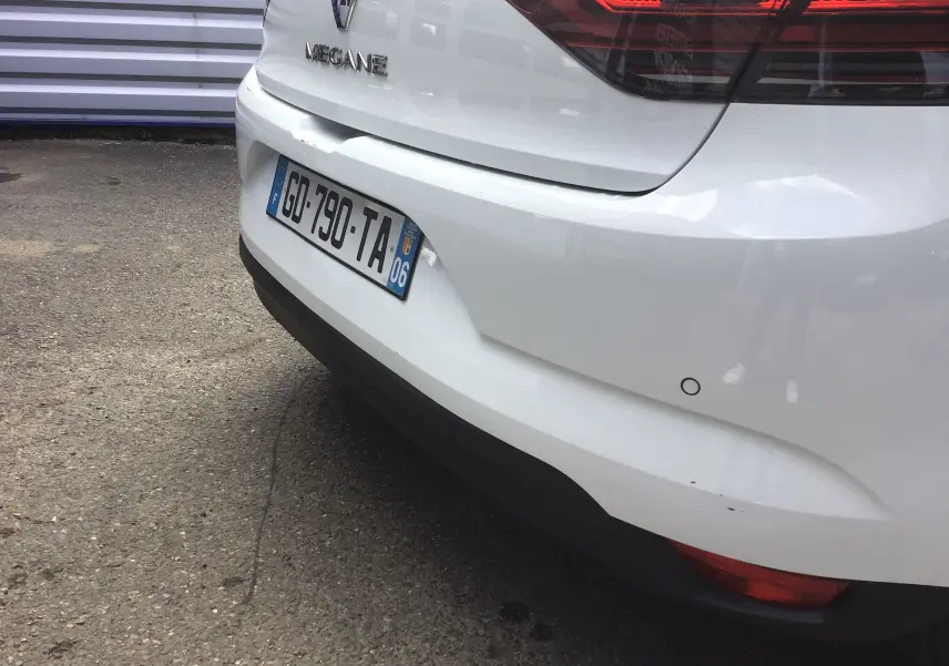 Vue arrière droite d'une Renault Mégane IV Société blanche avec plaque d'immatriculation française et feux arrière rouges.