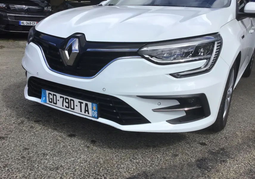 Vue avant droite d'une Renault Mégane IV Société blanche, mettant en valeur la calandre noire et les phares LED distinctifs.