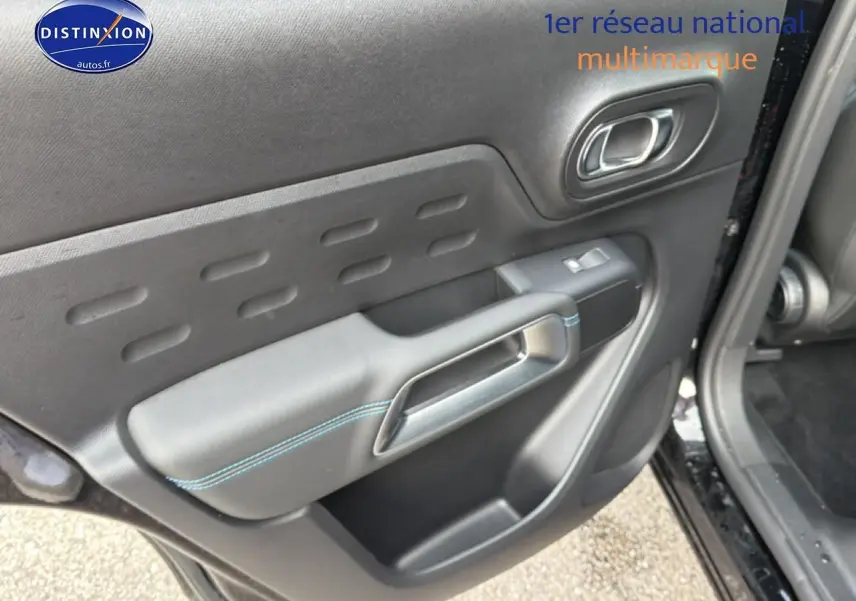 Gros plan sur la porte avant gauche noire perla nera du Citroën C5 Aircross avec surpiqûres bleues et poignée intégrée.