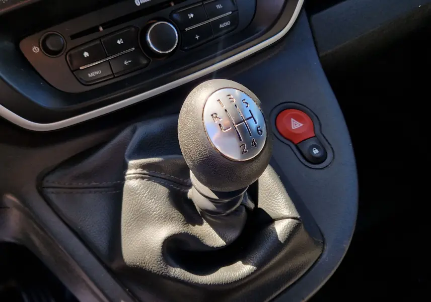 Gros plan sur le levier de vitesses manuel du Renault Kangoo blanc, avec bouton de warning rouge visible à droite.