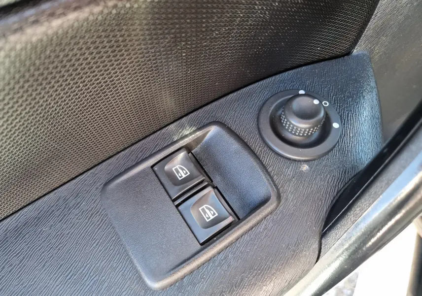 Gros plan sur les commandes de lève-vitres et réglage des rétroviseurs côté gauche d’un Renault Kangoo blanc 2021.