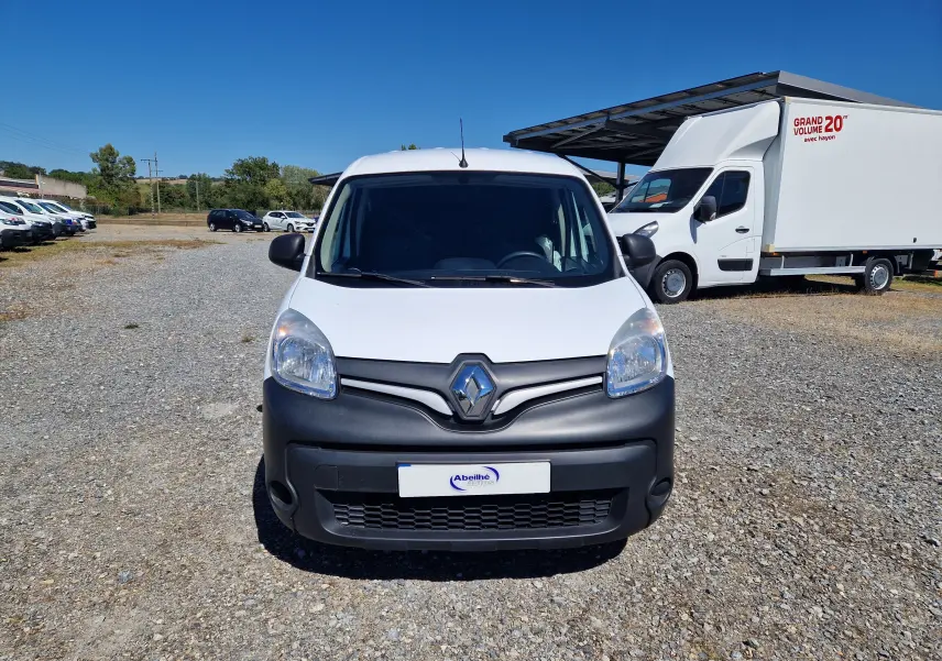 Vue avant d'un Renault Kangoo blanc 2021 avec pare-chocs noir mat, stationné sur un terrain gravillonné en extérieur.