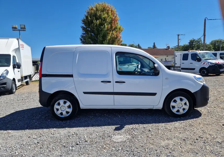 Renault Kangoo blanc vue 3/4 arrière droit, fourgonnette utilitaire avec portes arrière battantes, stationné en extérieur.