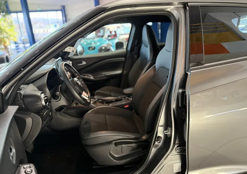 Intérieur côté conducteur du Nissan Juke Hybrid gris métallisé 2024 avec sièges mixte tissu et cuir noir.