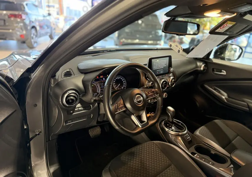 Intérieur du Nissan Juke Hybrid 2024 vu côté conducteur, avec tableau de bord noir et volant multifonction cuir.