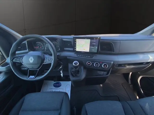 Vue intérieure frontale du tableau de bord du Renault Master 2025 avec volant, écran tactile et banquette passager grise.