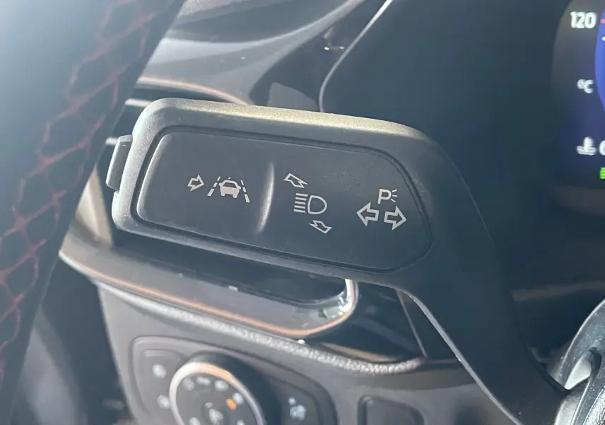 Gros plan sur la commande de clignotants et aides à la conduite dans le volant d’un Ford Puma gris 2020.