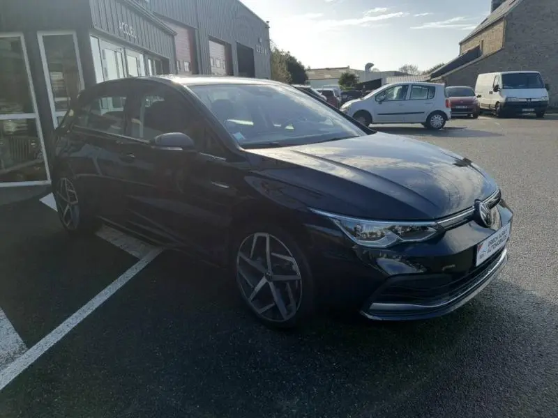 Volkswagen Golf noir intense nacrée vue 3/4 avant droit avec jantes alu 18 pouces et phares LED allumés.
