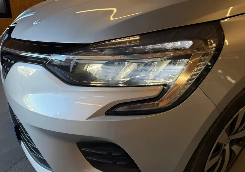Gros plan sur le phare avant droit gris platine d'une Renault Clio 1.0 TCE 90 Équilibre 2023 avec calandre noire.