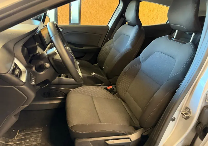 Vue intérieure côté conducteur de la Renault Clio 1.0 TCE 90 Équilibre 2023 avec sièges tissu gris et volant réglable.