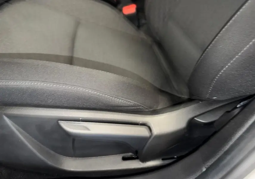 Gros plan sur le réglage manuel du siège conducteur en tissu gris dans une Renault Clio 2023, côté gauche.