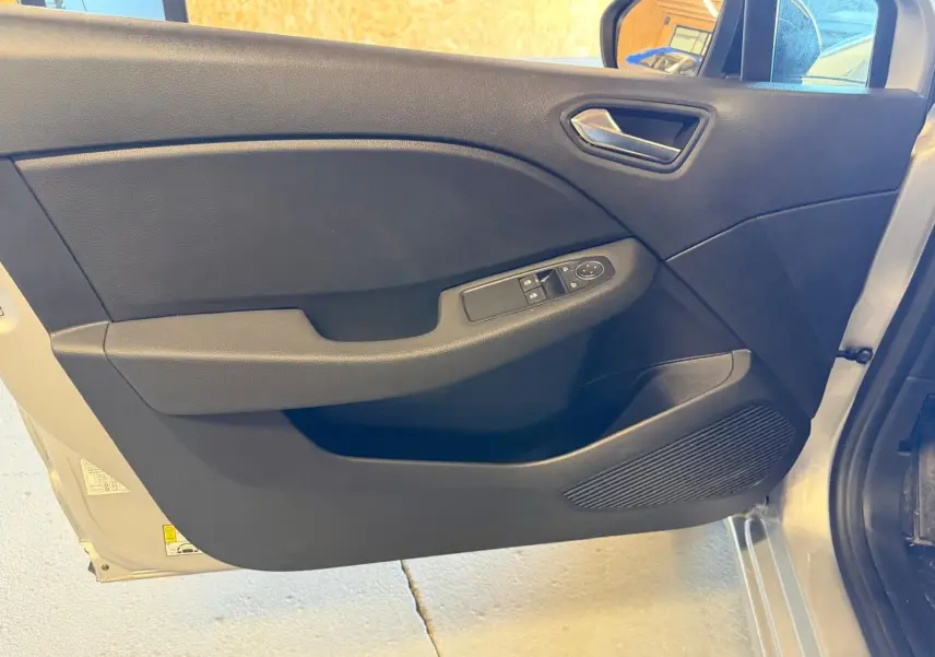 Vue intérieure côté gauche de la porte avant gris platine de la Renault Clio 2023 avec commandes de vitres électriques.