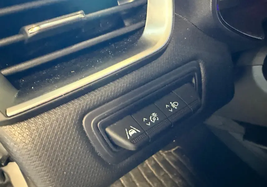 Gros plan sur les commandes d'aide à la conduite sur la console côté conducteur d'une Renault Clio gris platine 2023.