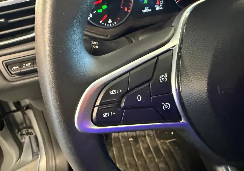 Gros plan sur le volant noir de la Renault Clio gris platine 2023, avec commandes du régulateur de vitesse visibles.