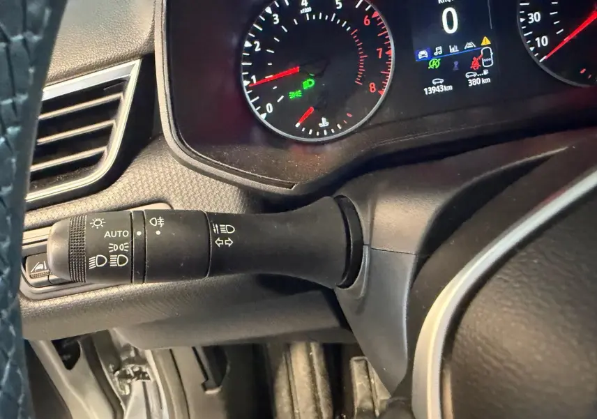 Vue rapprochée du commodo des feux et clignotants sur le volant noir d'une Renault Clio gris platine 2023.