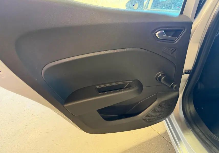 Vue rapprochée de la porte arrière gauche ouverte d'une Renault Clio gris platine, avec poignée et manivelle de vitre noire.