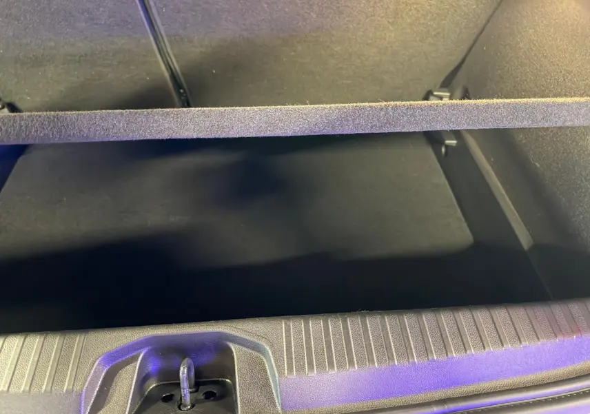 Vue intérieure du coffre ouvert de la Renault Clio gris platine, montrant la plage arrière et le tapis de coffre noir.