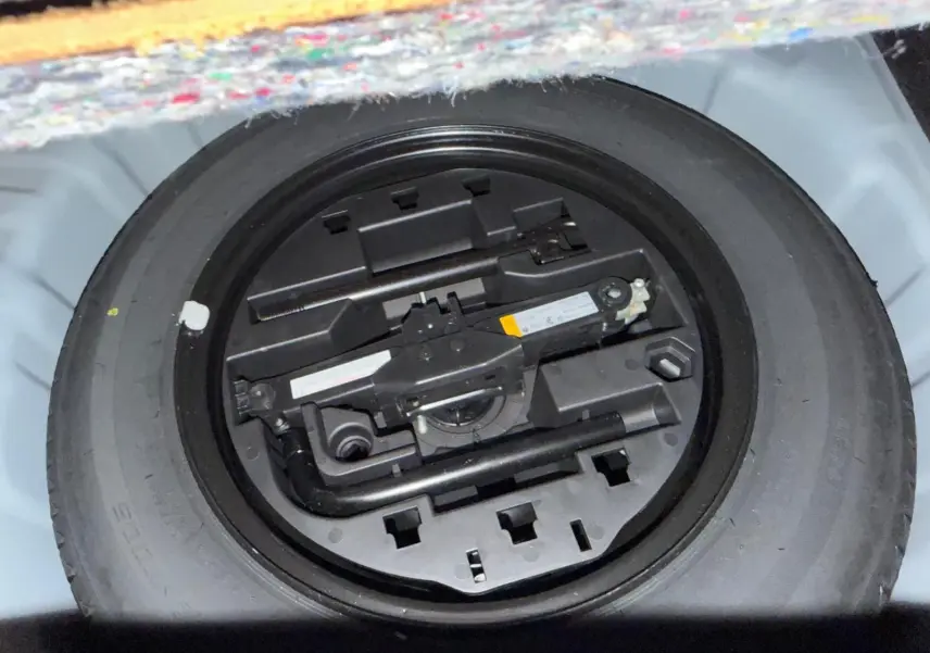 Pneu de secours avec outils de changement rangés dans le coffre d'une Renault Clio gris platine 2023.