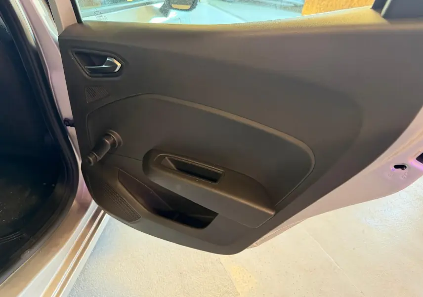 Vue rapprochée de la porte arrière gauche noire de la Renault Clio gris platine, avec poignée et manivelle de vitre.