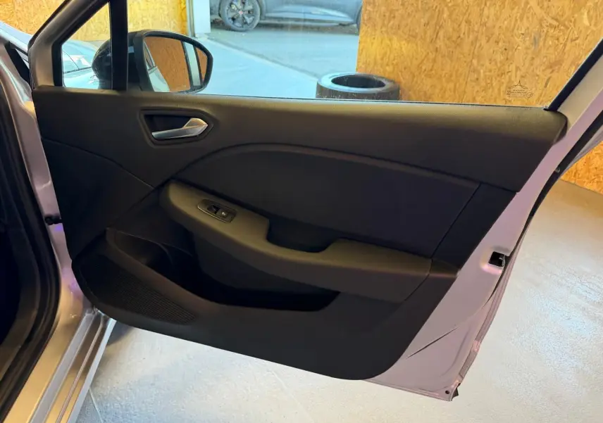 Vue intérieure de la porte arrière gauche gris platine de la Renault Clio 2023 avec commande de vitre électrique.