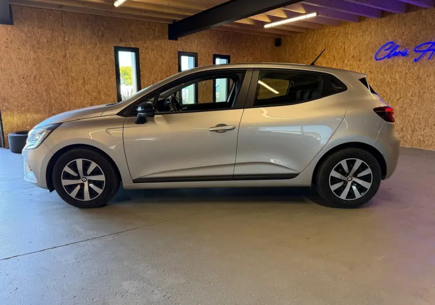 Profil côté gauche d'une Renault Clio 1.0 TCE 90 Équilibre gris platine, avec jantes et becquet arrière visible en intérieur.