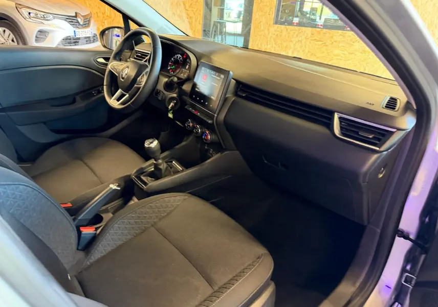 Vue intérieure côté conducteur de la Renault Clio gris platine 2023 avec tableau de bord et écran tactile.