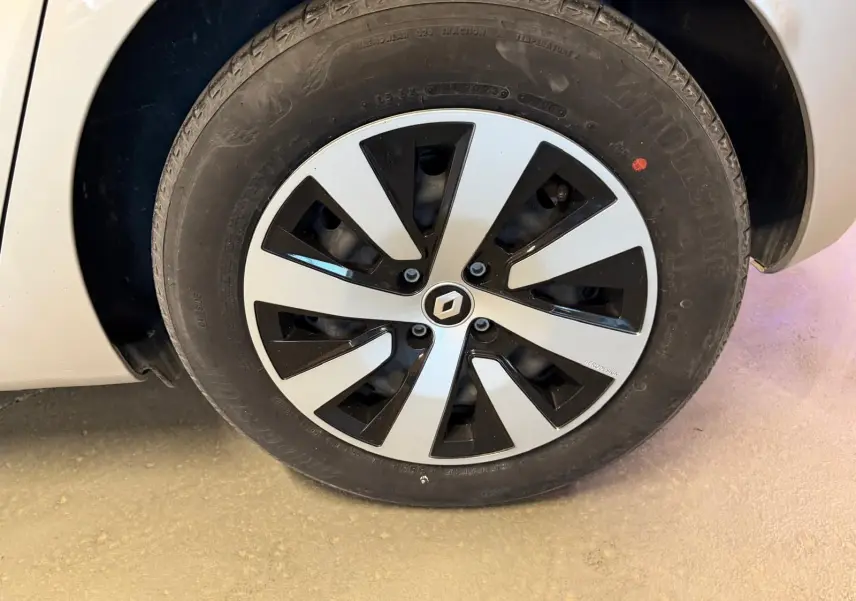 Gros plan sur la roue avant gauche d'une Renault Clio gris platine avec jante noire et argentée au design moderne.