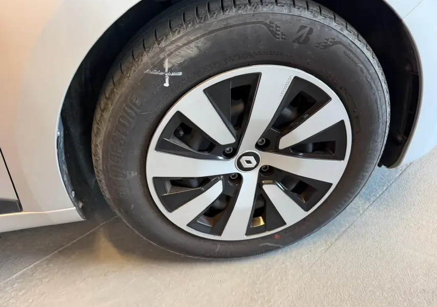 Gros plan sur la roue avant gauche grise platine d'une Renault Clio 2023 avec jante au design noir et argent.