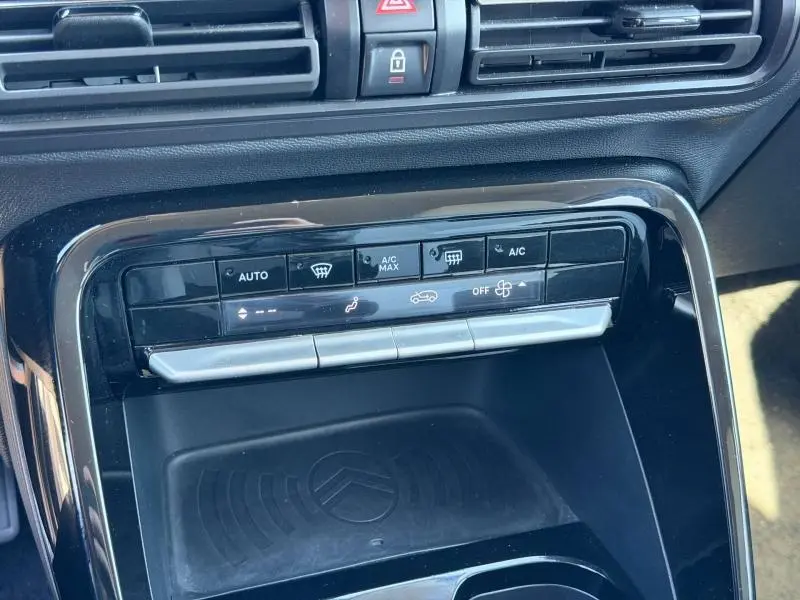 Vue rapprochée de la console centrale de la Citroën C3 2025 gris Mercury, montrant les commandes de climatisation et un espace de rangement.