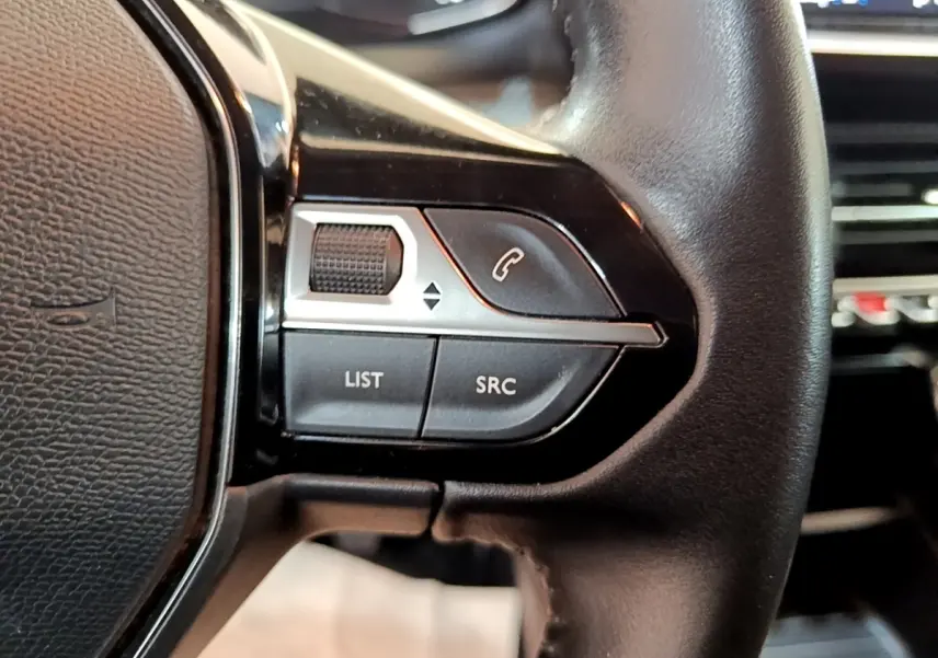 Gros plan sur le volant cuir noir du Peugeot 2008, avec commandes multifonctions côté gauche visibles.
