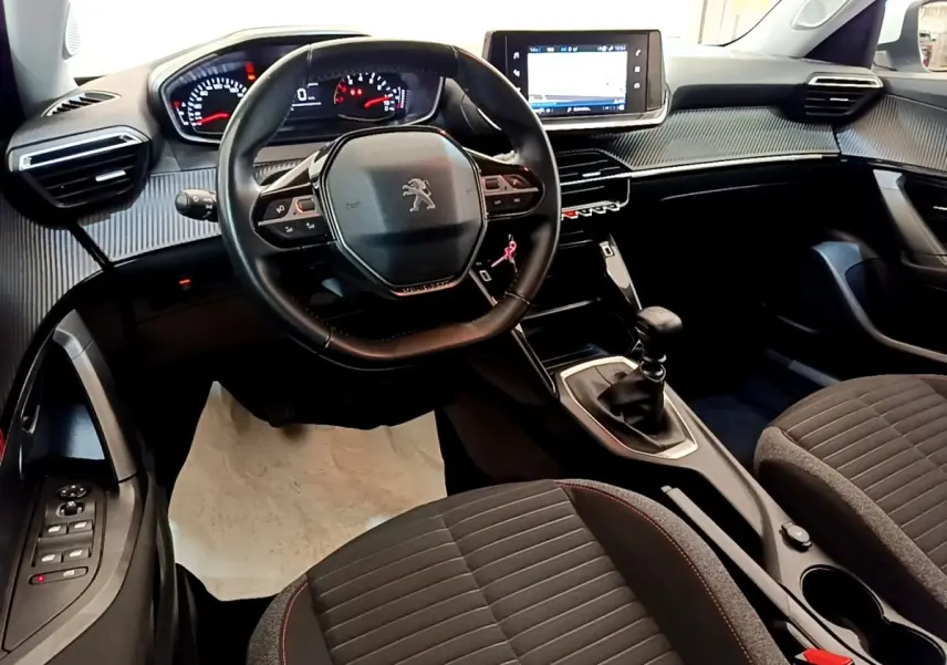 Vue intérieure avant du Peugeot 2008 avec volant cuir multifonctions, tableau de bord numérique et levier de vitesses manuel.