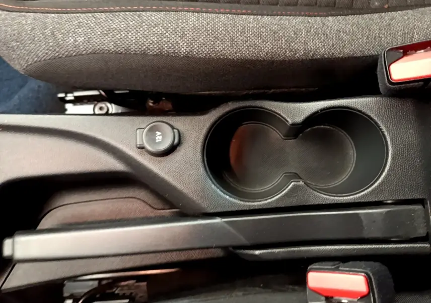 Vue rapprochée de la console centrale noire du Peugeot 2008 avec porte-gobelets et prise 12V.