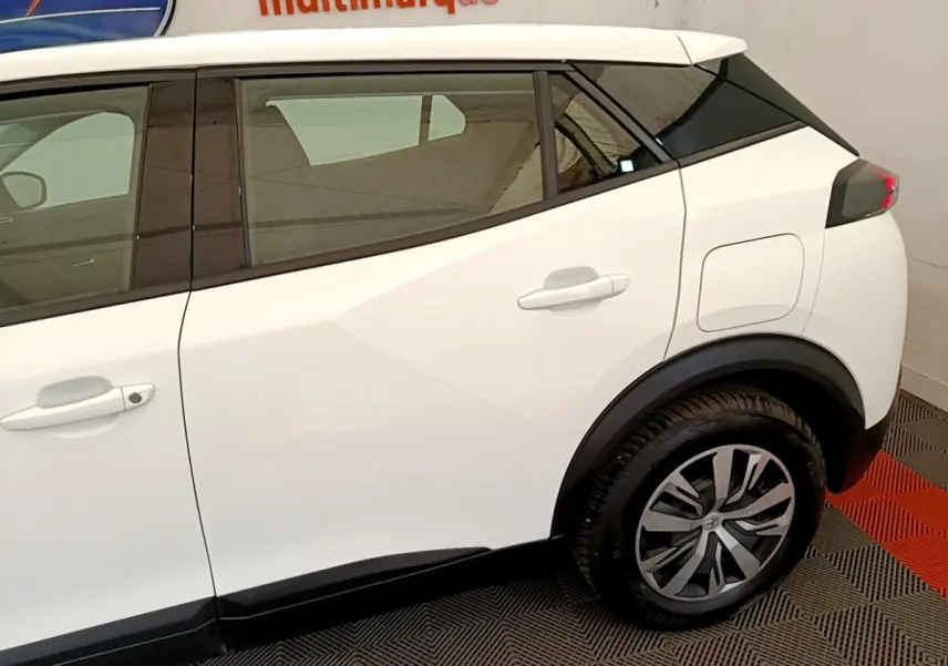 Vue latérale droite du Peugeot 2008 blanc, mettant en valeur les jantes alliage et les lignes anguleuses du profil arrière.