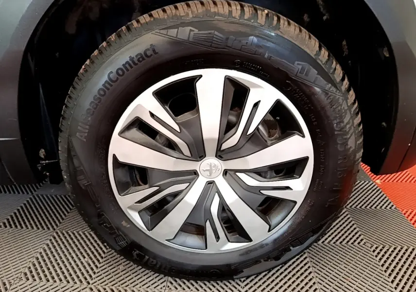 Gros plan sur la roue avant droite de la Peugeot 2008 blanche, avec jante alliage et pneu AllSeasonContact.