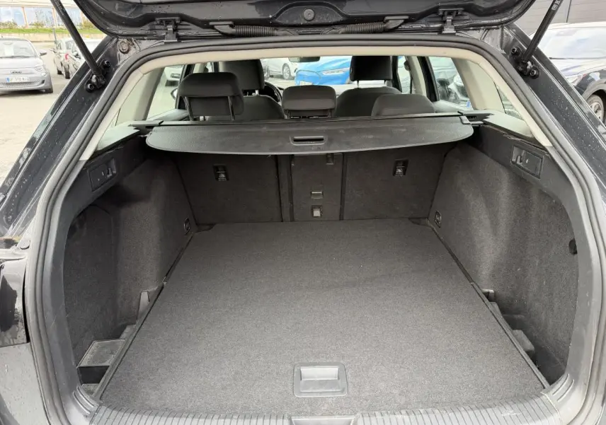Vue arrière du coffre ouvert d'une Volkswagen Golf SW gris foncé, montrant un espace de chargement vide et la plage arrière.