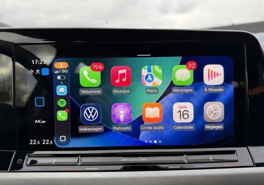 Écran tactile central affichant l'interface Apple CarPlay dans une Volkswagen Golf gris, vue de face intérieure.