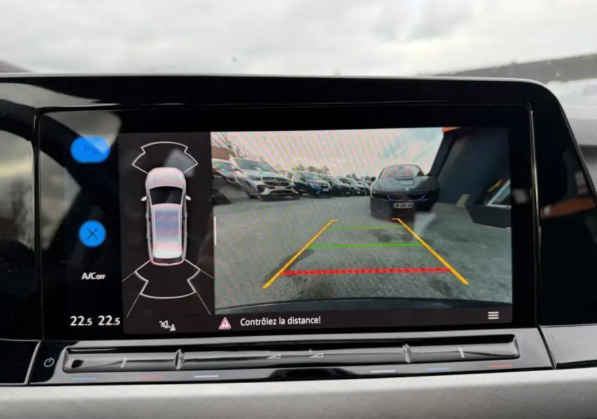 Écran de caméra de recul d'une Volkswagen Golf gris, vue arrière avec lignes de guidage colorées.