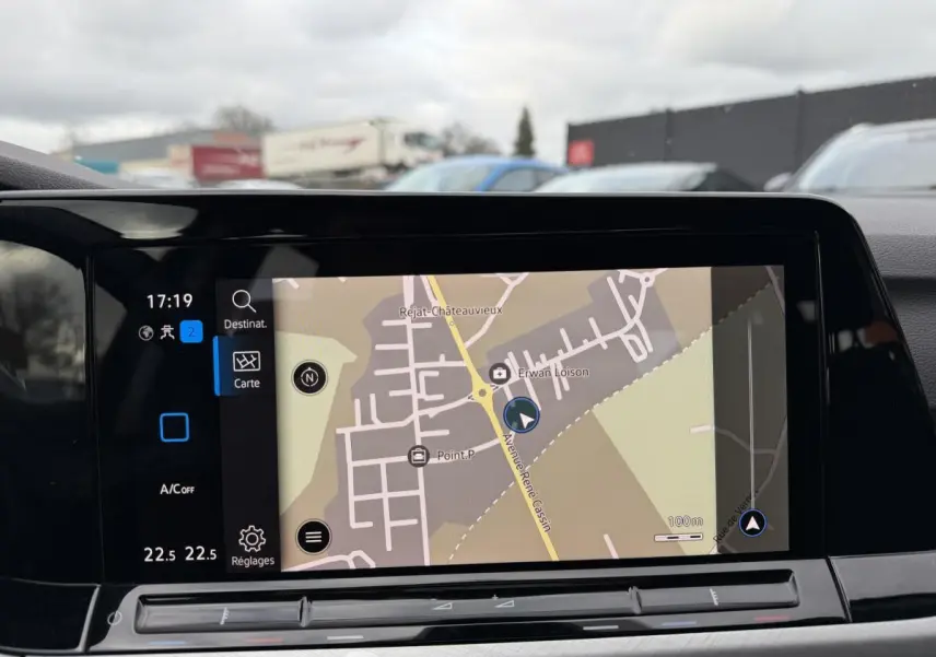 Vue intérieure sur l'écran tactile central du système de navigation d'une Volkswagen Golf gris, avec carte affichée.
