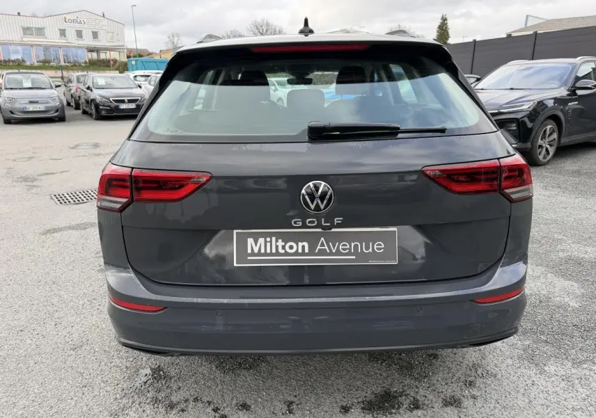Vue arrière d'une Volkswagen Golf SW gris Urano avec feux arrière LED et plaque Milton Avenue visible.