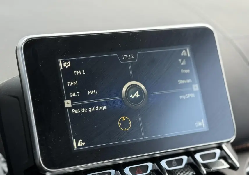 Écran tactile central de l'Alpine A110 1.8T 292 S affichant la radio FM et le logo Alpine, vue rapprochée intérieure.