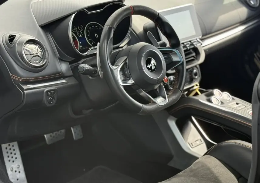 Vue intérieure côté conducteur de l'Alpine A110 1.8T 292 S 2020, volant cuir noir avec surpiqûres orange et tableau de bord moderne.