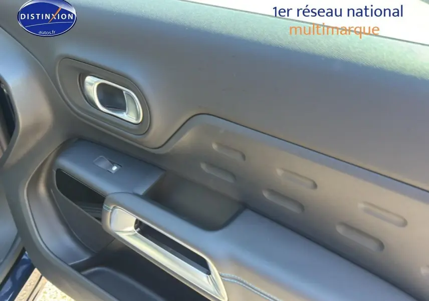 Gros plan sur la porte côté gauche du Citroën C5 Aircross bleu eclipse, avec poignée intérieure chromée et commande de vitre.
